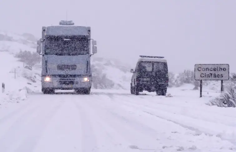 Um camião e um carro da GNR na estrada durante um nevão.
